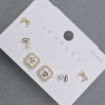 Aretes tipo botón en metal dorado con cristales blancos en forma de trébol 10 mm+